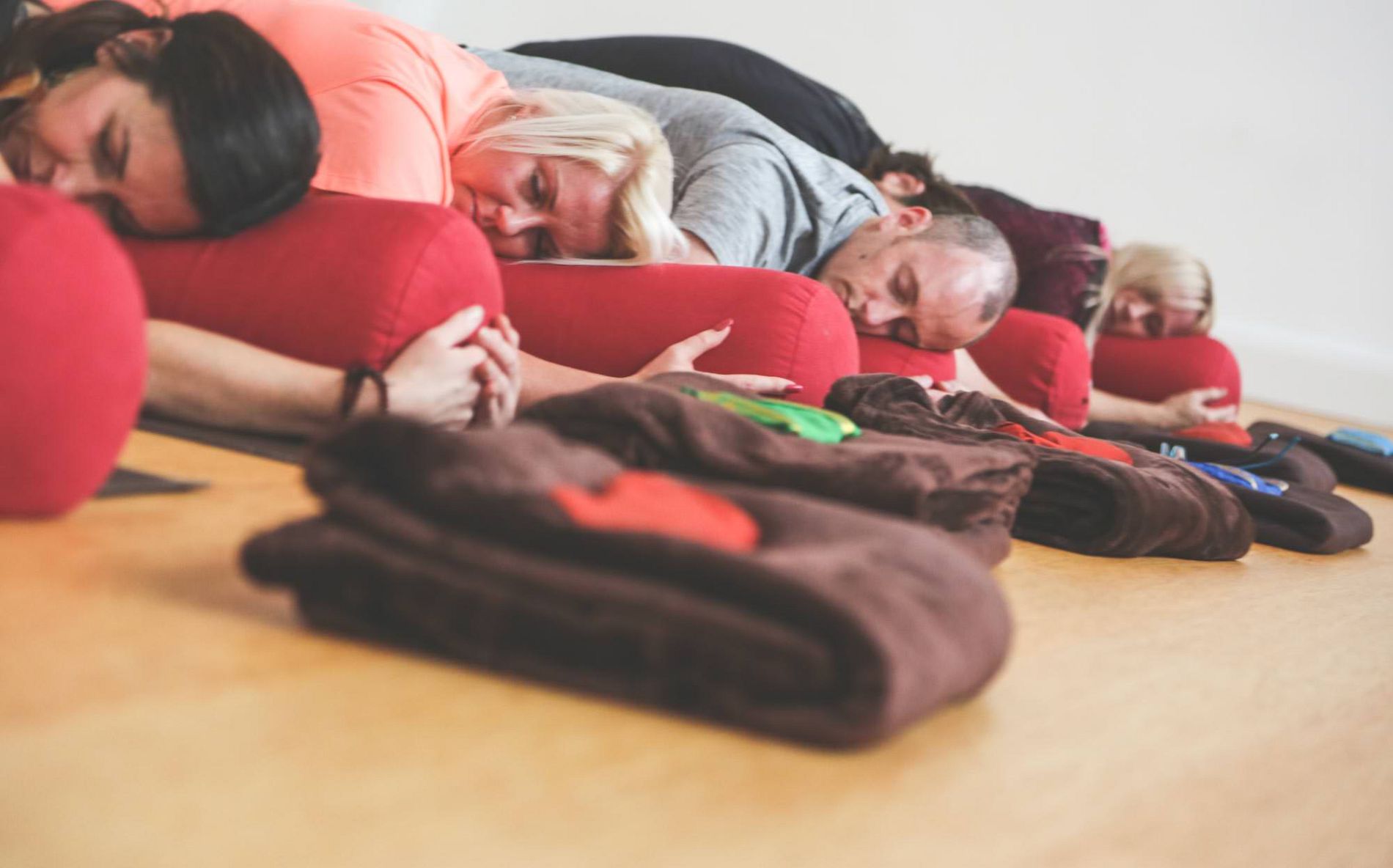 Students resting with bolsters during restorative yoga
